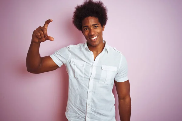 年轻的美国男子 一个头发 穿着白色衬衫站在孤立的粉红色背景微笑和自信的手势与手做小尺寸的标志 手指看和相机 测量概念 — 图库照片