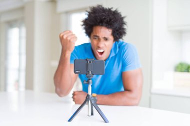 Afro-Amerikan adam akıllı telefon kullanarak web kamerası ile online arama yapıyor kızgın ve sinirli öfke ile bağırarak, deli ve yükseltilmiş el ile bağırıyor, öfke kavramı