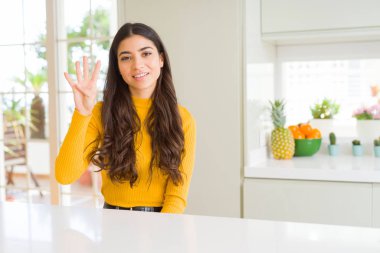 Beyaz masada evde genç güzel kadın gösteren ve parmak sayısı dört ile işaret kadar güven ve mutlu gülümseyen.
