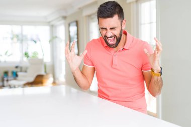 Yakışıklı İspanyol adam evde rahat t-shirt giyen silah kaldırdı ve kapalı gözleri heyecan çığlık ile başarı için deli ve deli kutluyor. Kazanan kavramı