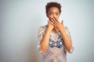 Beyaz izole arka plan üzerinde bir bikini giyen afro saçlı genç afro-amerikalı kadın hata için elleri ile ağız kapsayan şok. Gizli kavram.
