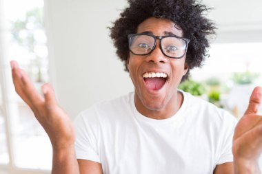Afrikalı-Amerikalı dostum deli ve çığlık kaldırdı ve açık gözleri heyecanlı silah ile başarı için hayran kutluyor gözlük takıyorsun. Kazanan kavramı