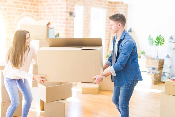 Schönes junges Paar, das verliebt lächelt und einen großen Karton in der Hand hält — Stockfoto