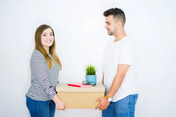 Jovem lindo casal segurando caixa de papelão sobre isolado branco — Fotografia de Stock