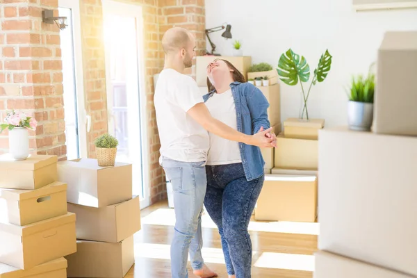 Молода пара танцює навколо картонних коробок в новому будинку, Кіт — стокове фото
