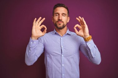 Mor izole arka plan üzerinde zarif gömlek giyen genç iş adamı dinlenmek ve parmakları ile meditasyon jest yapıyor kapalı gözleri ile gülümseyerek. Yoga konsepti.
