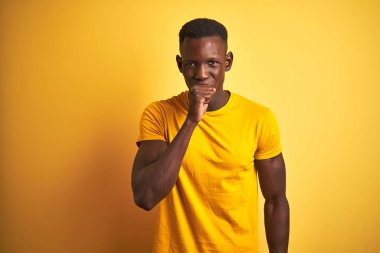 Genç afro-Amerikan adam izole sarı arka plan üzerinde ayakta rahat t-shirt giyen rahatsız duygu ve soğuk veya bronşit için bir belirti olarak öksürük. Sağlık kavramı.