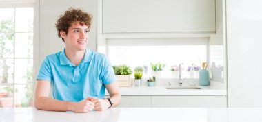 Evde genç yakışıklı adam geniş çekim yüzünde gülümseme, doğal ifade ile yan bakıyor. Gülmekten emin.