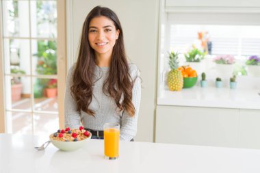 Sabahları sağlıklı kahvaltı yiyen genç kadın yüzünde mutlu ve serin bir gülümseme ile. Şanslı kişi.