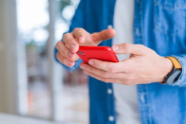 Primer plano de las manos del hombre usando el teléfono inteligente y sonriendo —  Fotos de Stock