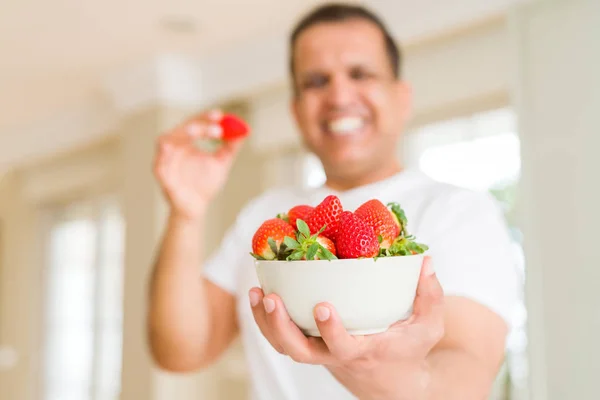 Hombre de mediana edad comiendo fresa en casa —  Fotos de Stock