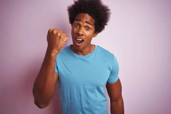 非洲裔美国男子 一个非洲头发 穿着蓝色T恤站在孤立的粉红色背景愤怒和疯狂的提高拳头沮丧和愤怒 而愤怒地喊道 愤怒和侵略性的概念 — 图库照片