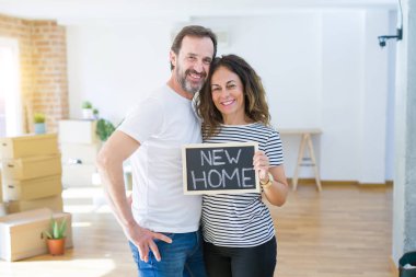 Orta yaş Senior çift yeni bir eve hareket, yeni bir ev metin ile bir tahta tutan Apartmant aşık mutlu gülümseyen