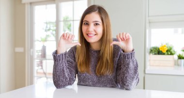 Güzel genç kadın evde kendini gururlu ve mutlu parmakları ile işaret emin yüz, gülümseme ile seyir.