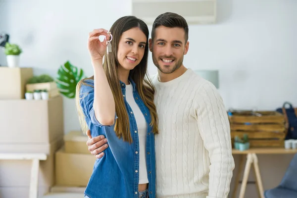 Ungt par flyttar till ett nytt hem, kramas i kärlek visar nycklar — Stockfoto