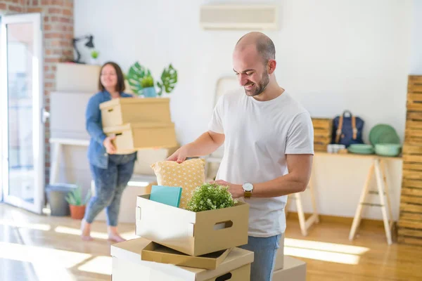 Young couple moving to new apartment, handsome man leaning on cardboard boxes and smiling happy