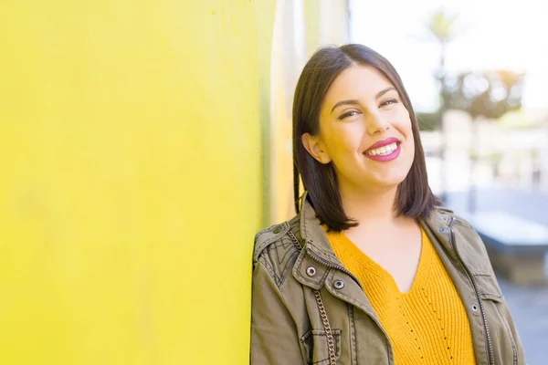 Mooie jonge vrouw glimlacht zelfverzekerd en vrolijk leunend op — Stockfoto