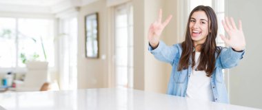 Geniş açı resim gösterme ve parmak yedinci ile gülümseyen ise kendinden emin ve mutlu yukarıyı evde beyaz masaya oturan güzel genç kadın.