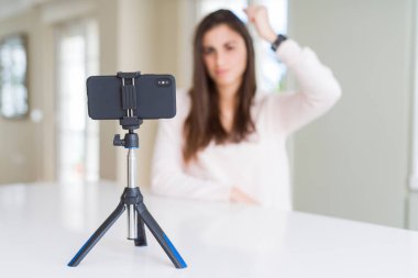 Akıllı telefon web kamerası ile selfie video kayıt güzel genç kadın kızgın ve sinirli öfke, deli ve yükseltilmiş el, öfke kavramı ile bağırarak