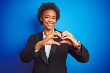 Izole mavi arka plan üzerinde Afro-Amerikan iş yönetici kadın sevgi kalp sembolü ve elleriyle şekil gösteren gülümseyerek. Romantik kavram.