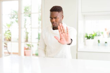 Yakışıklı afro-amerikan adam beyaz masada avuç içi ile şarkı durdurmak yapıyor. Yüzünde olumsuz ve ciddi bir jest olan uyarı ifadesi.
