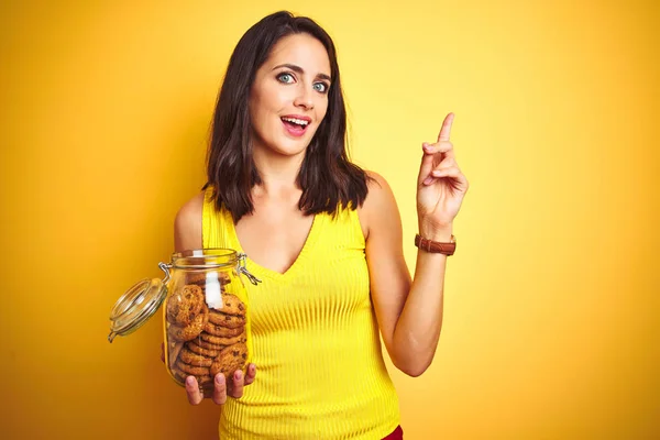 Jovem Bela Mulher Segurando Frasco Biscoitos Sobre Fundo Isolado Amarelo — Fotografia de Stock