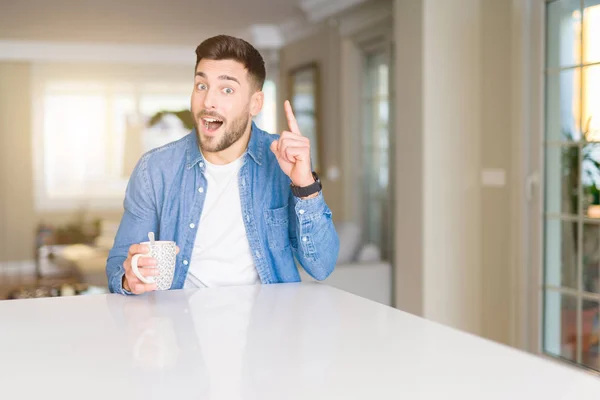 Jovem Bonitão Bebendo Uma Xícara Café Casa Surpreso Com Uma — Fotografia de Stock