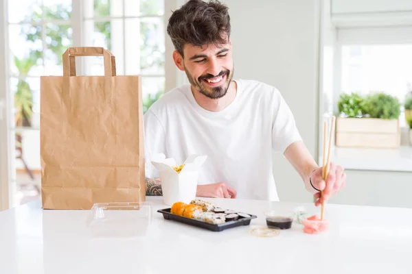 Young man eating sushi asian food and noodles using choopsticks