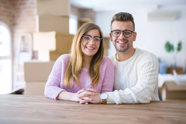 Young beautiful couple sitting on the table at home, hugging in