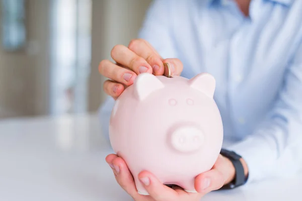 Close-up van de hand van de man brengen van een munt binnenkant piggy bank als savi — Stockfoto
