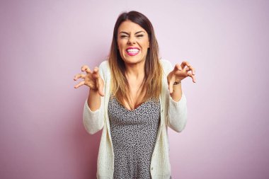 Genç güzel kadın pembe izole arka plan üzerinde duran komik kedi, agresif ve seksi ifade olarak pençe jest yapıyor gülümseyerek