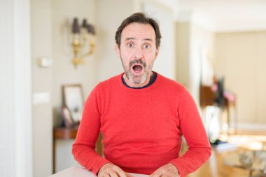 Yakışıklı orta yaş adam evde korkmuş ve sürpriz ifade, korku ve heyecanlı yüz ile şok.