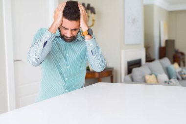 Evde yakışıklı İspanyol adam baş ağrısı umutsuz muzdarip ve stresli çünkü ağrı ve migren. Eller baş üstünde.