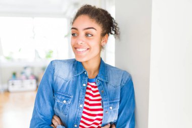 Afro saçlı rahat denim ceket görünümlü yan ve dik dik bakma uzağa düşünce gülümseyen güzel genç Afro-Amerikan kadın.