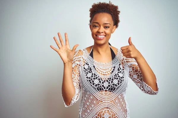Young african american woman with afro hair wearing a bikini over white isolated background showing and pointing up with fingers number six while smiling confident and happy.