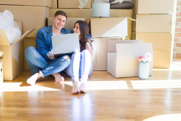 Junges Paar sitzt auf dem Boden des neuen Hauses um Pappe herum — Stockfoto