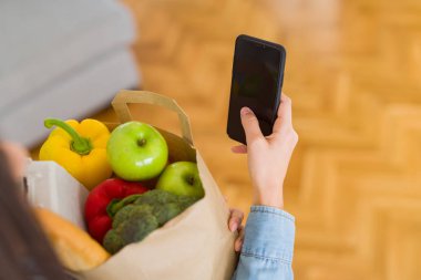 Taze bakkal ve istimal dolu bir kağıt çanta tutan genç kadın
