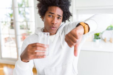 Afrika kökenli Amerikalı adam kızgın yüzü, eksi işareti aşağı antipati başparmak ile gösterilen, ret kavramı ile evde su içme