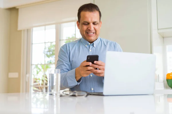 Hombre de mediana edad que trabaja con el ordenador portátil y el uso de smartphone —  Fotos de Stock