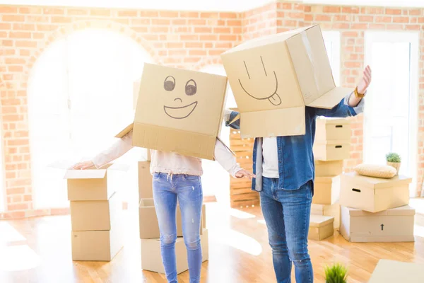 Casal se divertindo no novo apartamento vestindo caixas com rosto engraçado — Fotografia de Stock