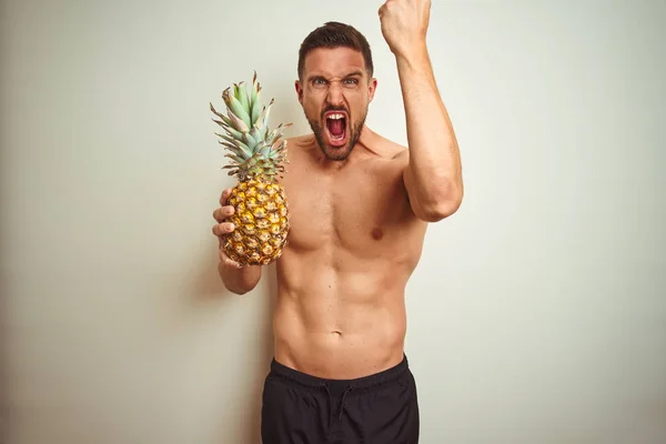 Handsome Shirtless Man Wearing Swimwear Holding Pineapple Isolated Background Annoyed — Stock Photo, Image