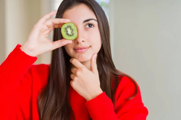 Hermosa Mujer Joven Comiendo Medio Kiwi Verde Fresco Cara Seria — Foto de Stock