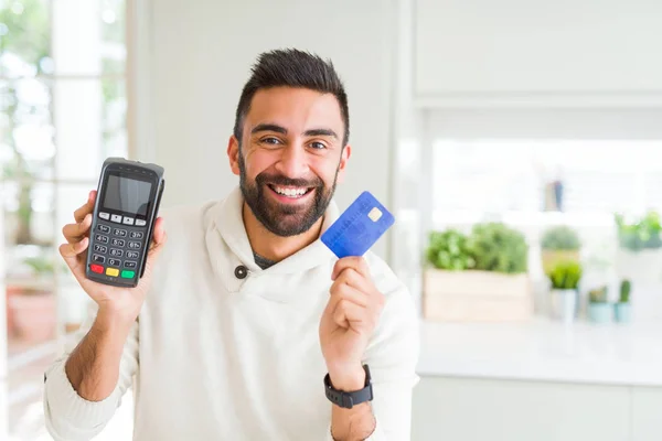 Hombre de negocios sonriendo y sosteniendo punto de venta terminal y cred —  Fotos de Stock