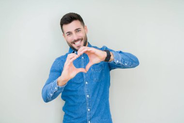 Yakışıklı delikanlı aşık kalp simgesi ve elleriyle şekil gösteren gülümseyen izole arka plan üzerinde. Romantik kavramı.