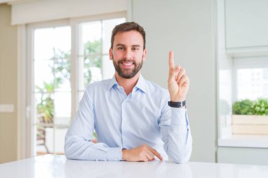 Yakışıklı iş adamı gösteren ve kendinden emin ve mutlu gülümserken parmak bir numara ile işaret.