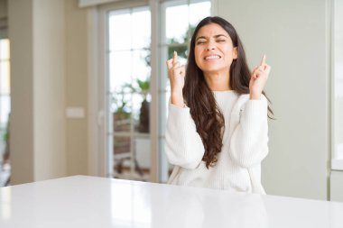 Beyaz masa üzerinde Evde Genç güzel kadın umut ve gözleri ile parmak geçiş gülümseyen kapalı. Şans ve batıl fikir.