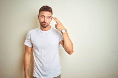 Genç yakışıklı adam izole arka plan üzerinde rahat beyaz t-shirt giyen Çekim ve kendini silah gibi baş el ve parmakları gösteren öldürme, intihar jesti.