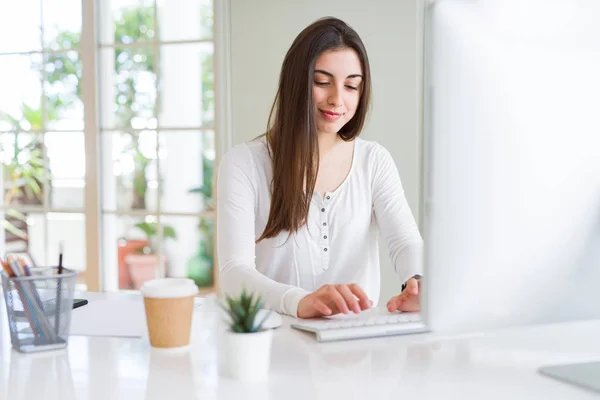 Красива молода бізнес-леді працює за допомогою комп'ютера, посміхаючись — стокове фото