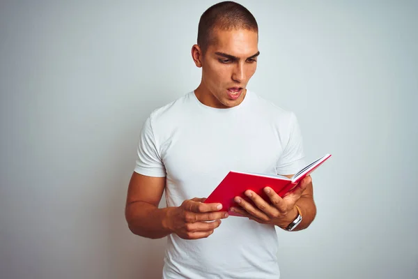 Young Handsome Man Reading Red Book White Isolated Background Scared — Stock Photo, Image