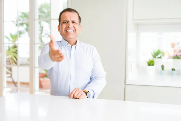 自宅に座っている中年の男は 挨拶と歓迎として握手を提供する友好的な笑顔 ビジネスの成功 — ストック写真